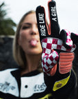 A woman showing two fingers with ride like a girl text on her motorcycle gloves