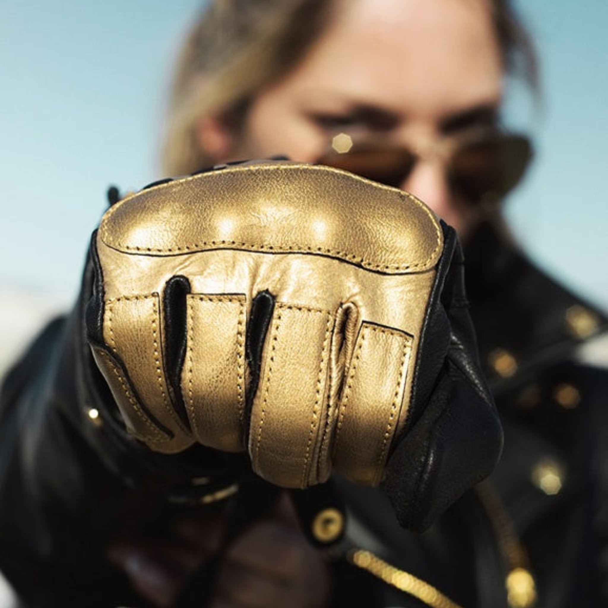 woman's fist wearing black Eudoxie mc glove with golden flames 