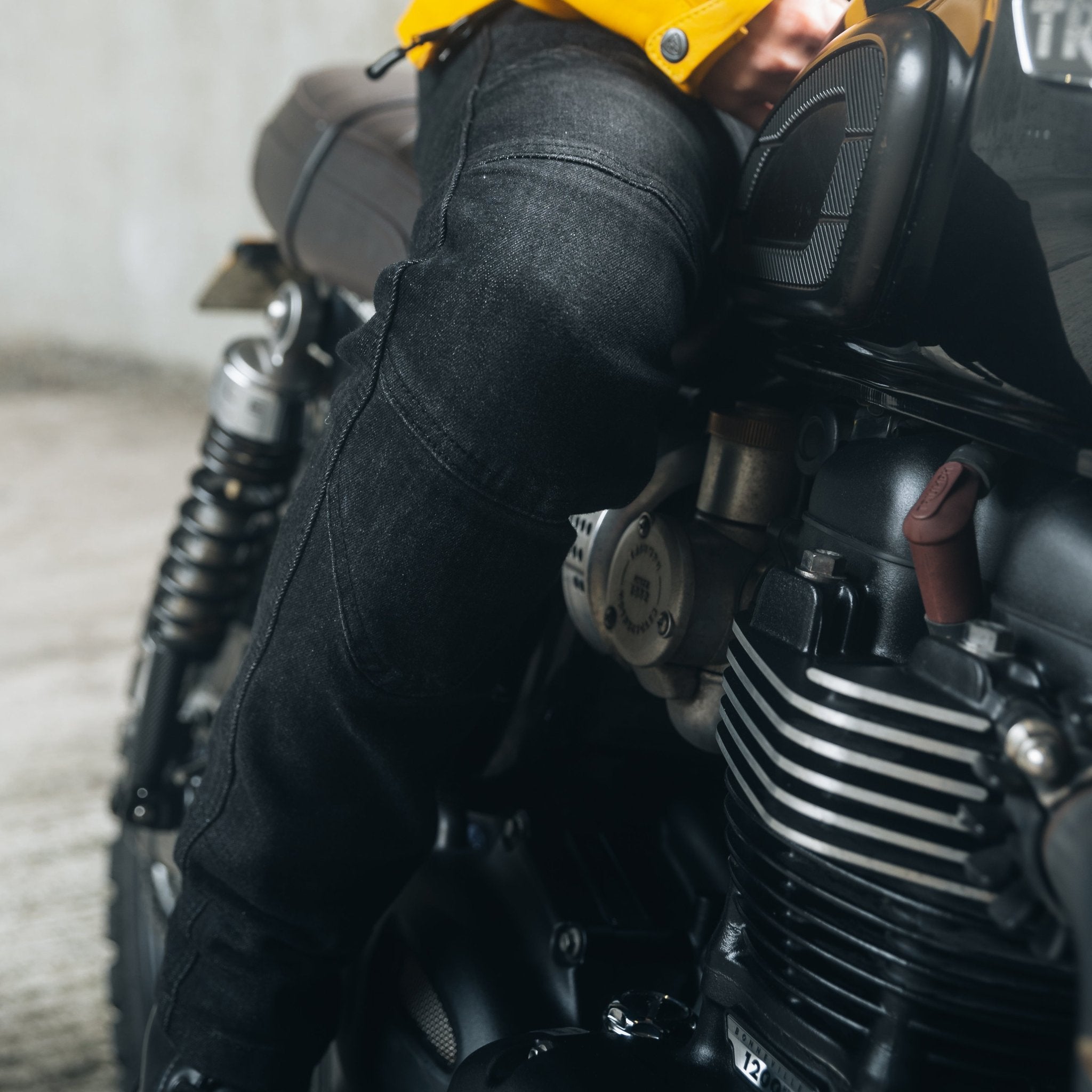 A woman's leg as she sits on a motorcycle, wearing black lady motorcycle jeans from Moto Girl.