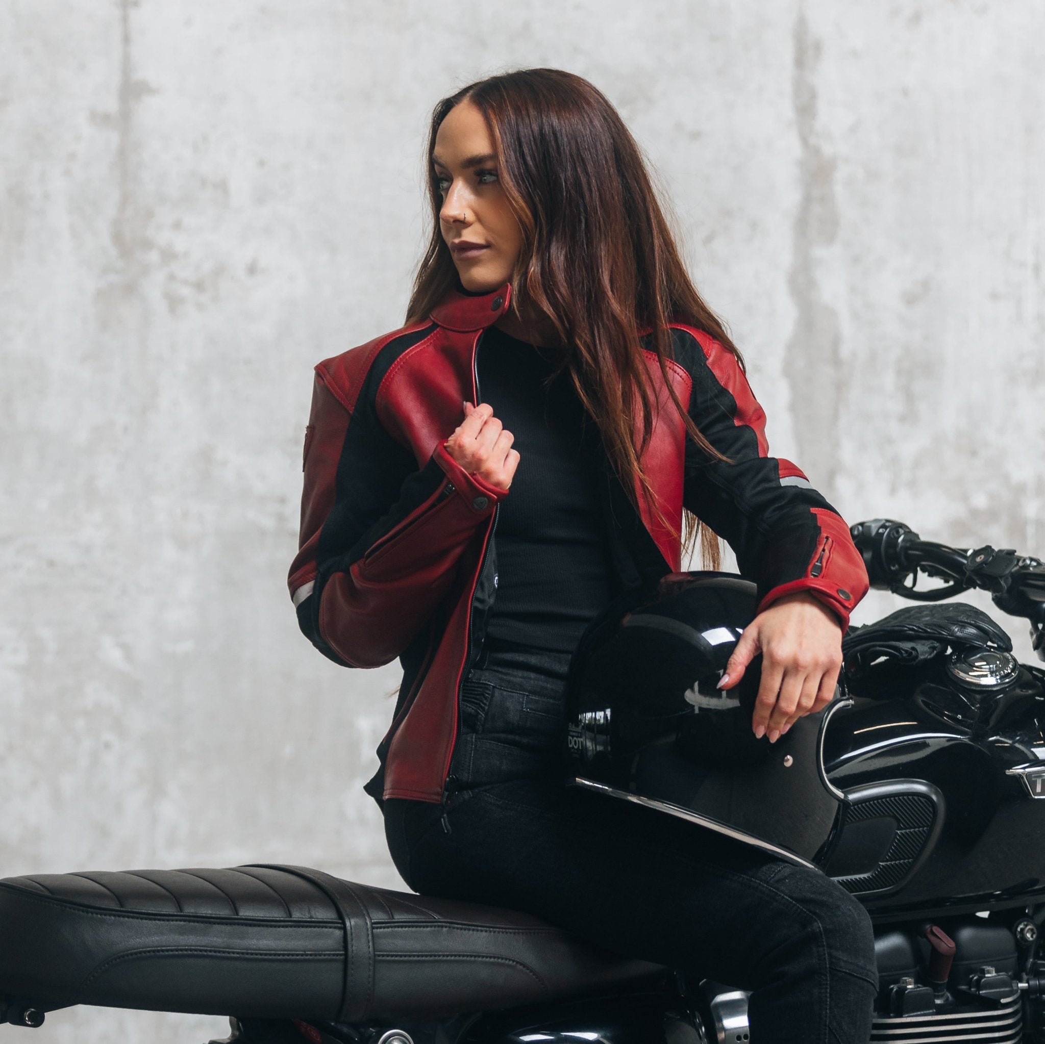 
A young woman on her motorcycle wearing a red and black women&#39;s motorcycle jacket with reflectors on the sleeves.